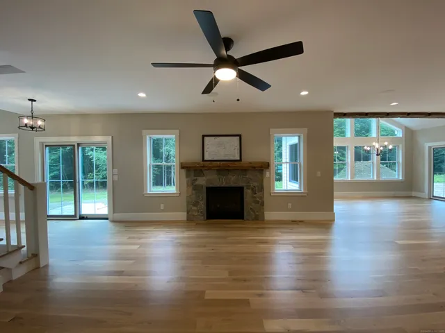 an empty room with wooden floor fireplace and windows