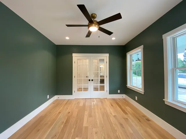 a view of empty room with wooden floor and fan