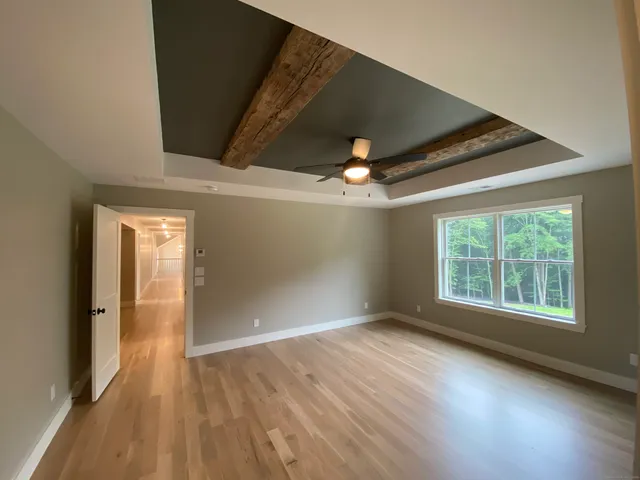 an empty room with wooden floor fan and windows