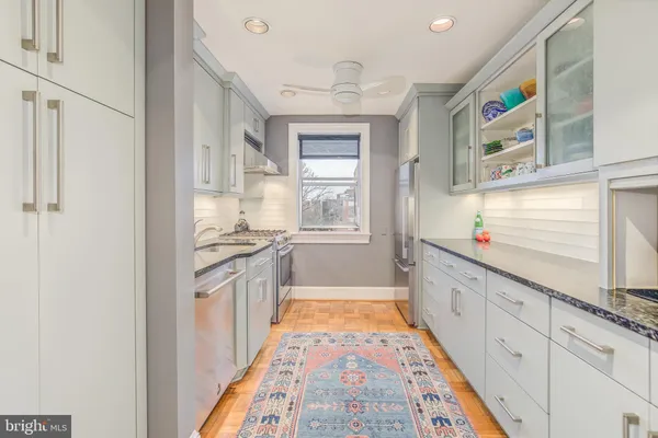 a large white kitchen with stainless steel appliances granite countertop a refrigerator and a stove