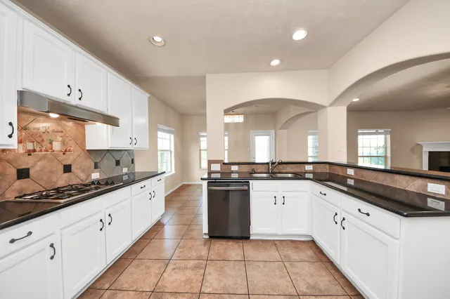 a large kitchen with stainless steel appliances granite countertop a sink and cabinets