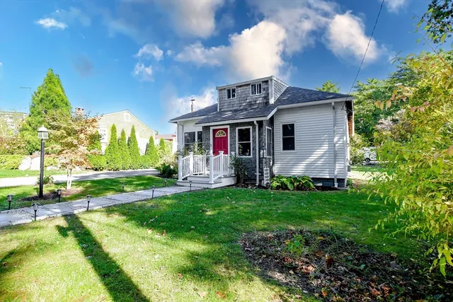 a view of a house with a big yard potted plants and large tree