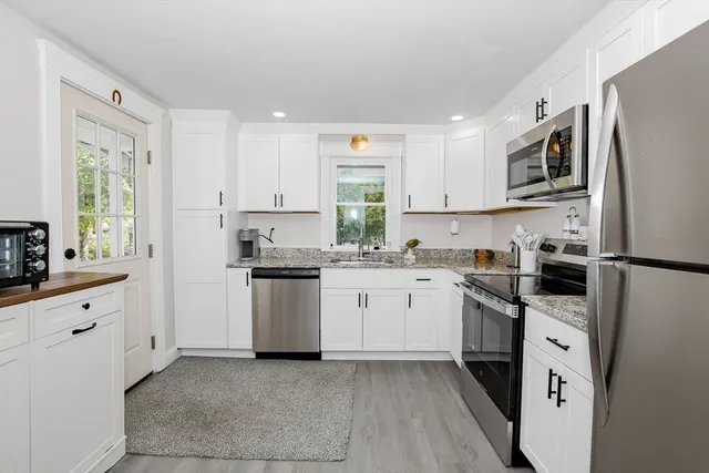 a kitchen with granite countertop white cabinets white stainless steel appliances with a sink and dishwasher