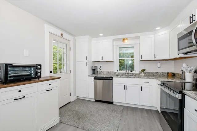 a kitchen with granite countertop white cabinets and white appliances
