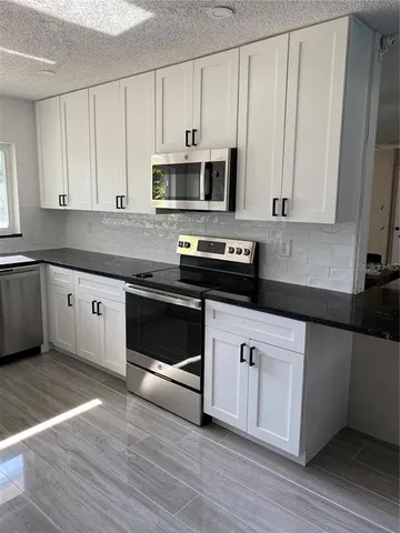 a kitchen with stainless steel appliances granite countertop a stove a sink and a microwave