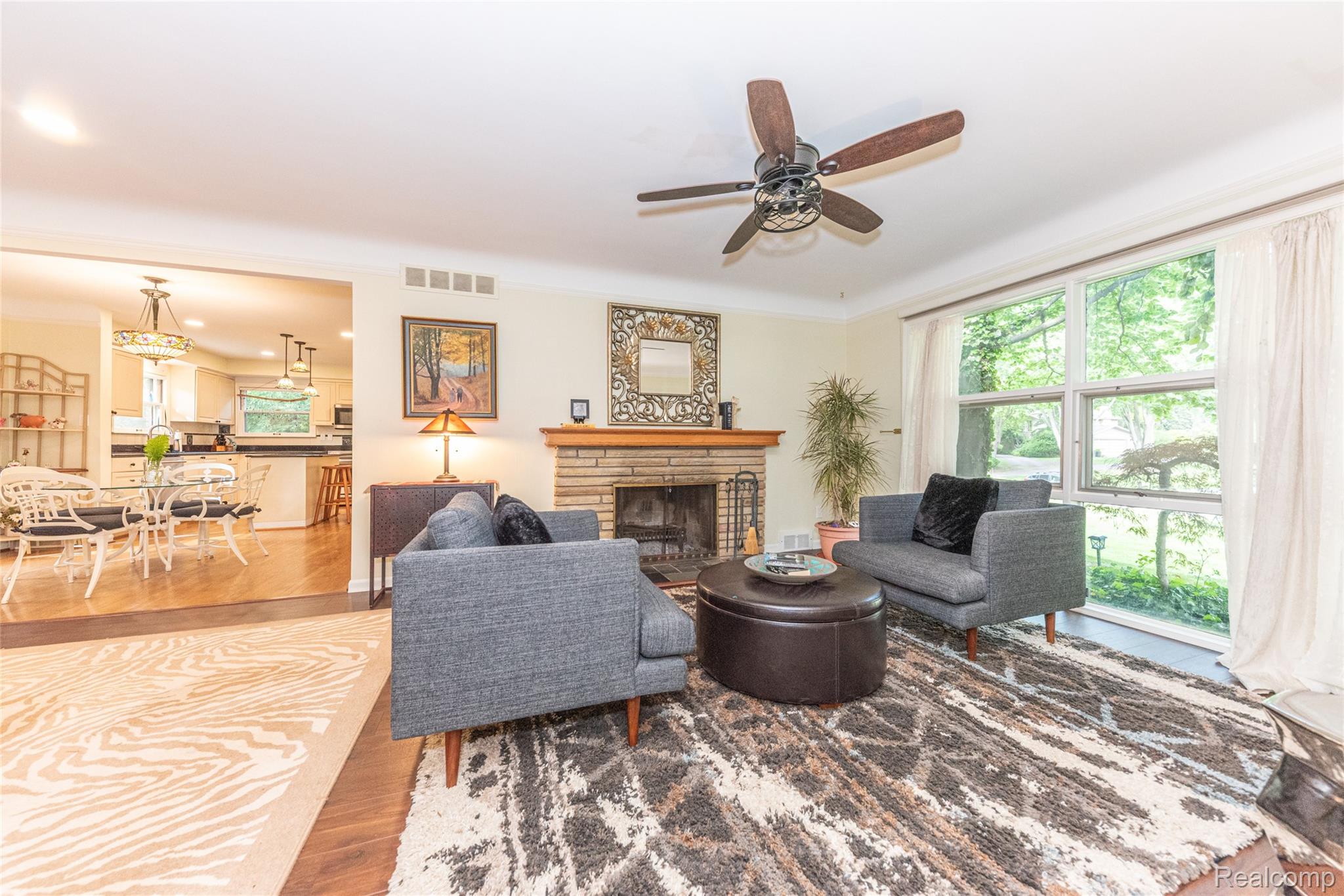 3887 Stonecrest Road West Bloomfield, MI 48322 - Photo 31 of 45 Living area featuring a brick-surround fireplace with a wood mantel, a ceiling fan, and large windows