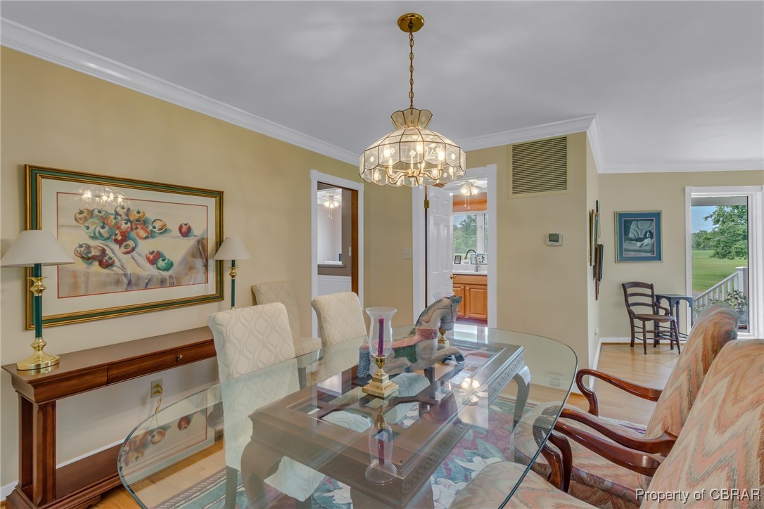 86 Greenfield Road Lancaster, VA 22503 - Photo 21 of 44 Dining space with ornamental molding, a chandelier, light wood-style flooring, and baseboards