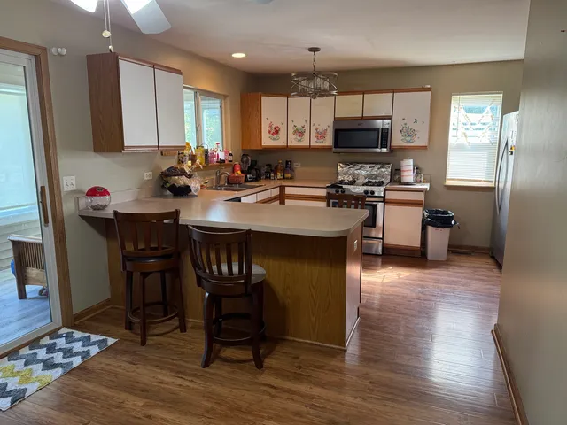 a kitchen with stainless steel appliances granite countertop a sink dishwasher a stove a refrigerator a microwave oven with cabinets and wooden floor