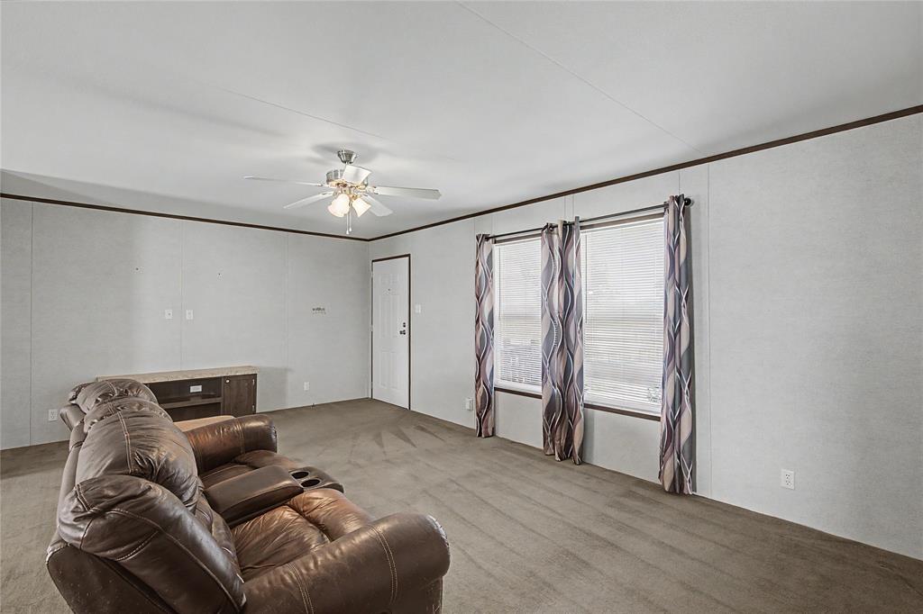 177 New Highland Road Springtown, TX 76082 - Photo 10 of 40 Living space featuring light-colored walls with dark trim, neutral carpet, and a ceiling fan with integrated lighting