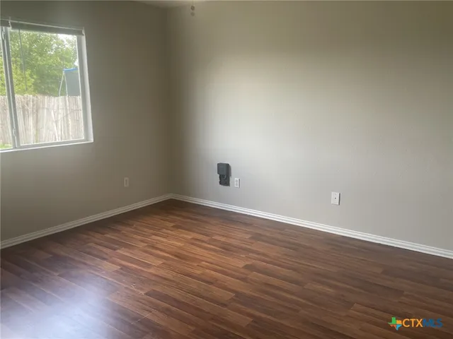a view of an empty room with wooden floor and windows