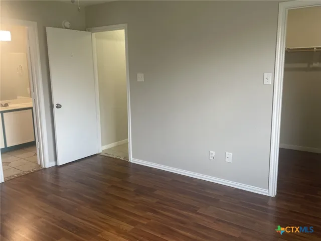 a view of an empty room with wooden floor and closet