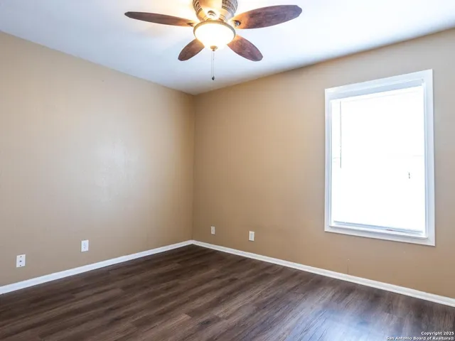 an empty room with wooden floor cabinet and windows