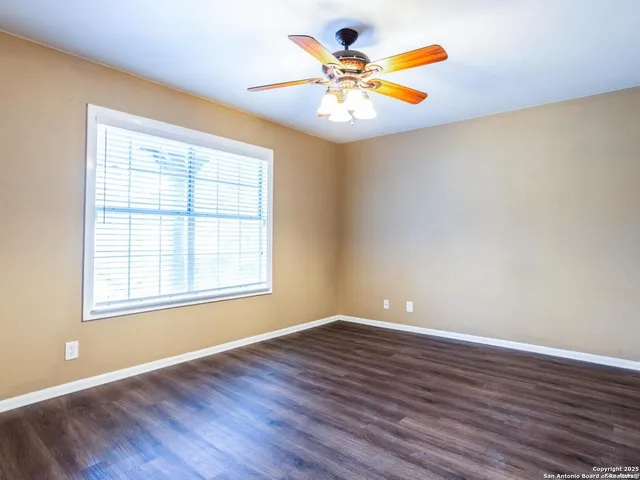 a view of an empty room with a window and wooden floor