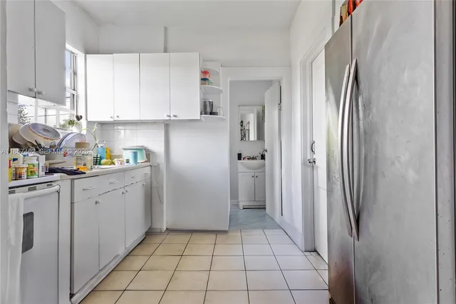 a kitchen with white cabinets and refrigerator