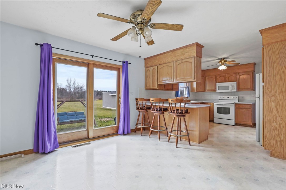 411 Adario West Road Shiloh, OH 44878 - Photo 5 of 35 Kitchen with white appliances, plenty of natural light, backsplash, and a kitchen bar