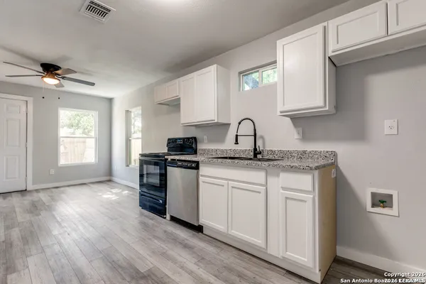 a kitchen with stainless steel appliances granite countertop a sink cabinets a stove and a window
