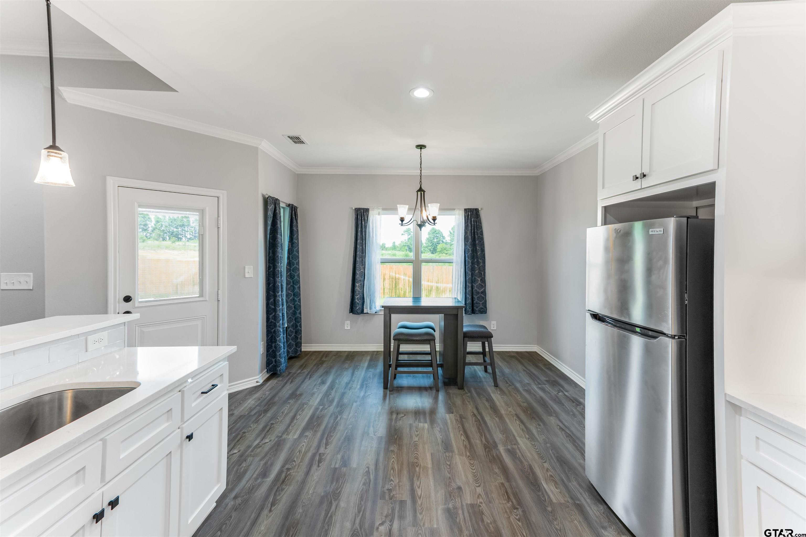 12908 County Road 46 Tyler, TX 75704 - Photo 7 of 20 a kitchen with stainless steel appliances a refrigerator a sink dishwasher and white cabinets with wooden floor
