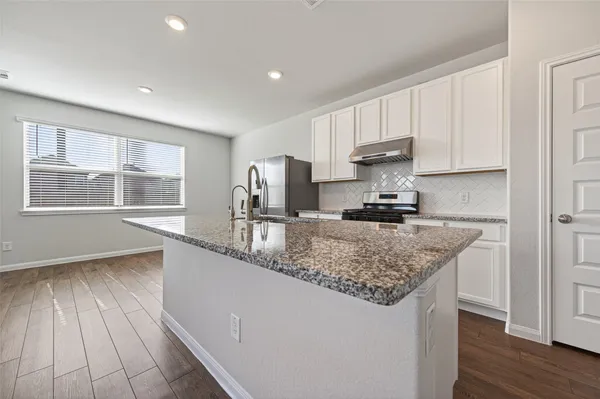 a kitchen with stainless steel appliances granite countertop a sink a stove a refrigerator and cabinets