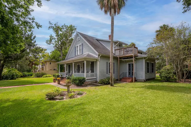 a front view of a house with garden and trees