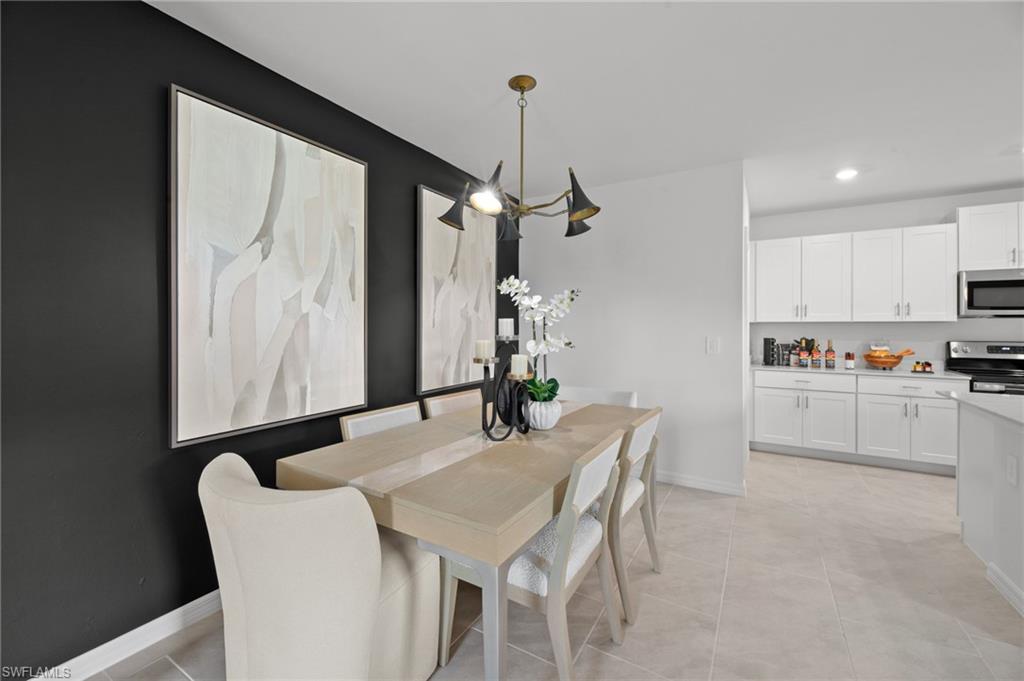 7182 Sugar Pine Way Fort Myers, FL 33966 - Photo 12 of 36 a kitchen with stainless steel appliances kitchen island granite countertop a table chairs and a refrigerator