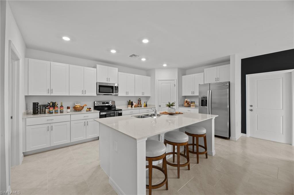 7182 Sugar Pine Way Fort Myers, FL 33966 - Photo 6 of 36 a kitchen with a sink a stove a refrigerator and white cabinets