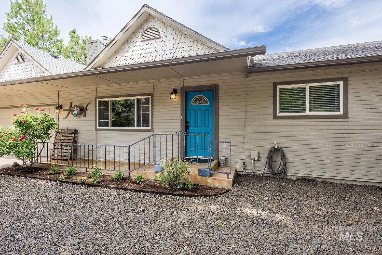 7166 South Cloverdale Road Boise, ID 83709 - Photo 2 of 50 Gable roof with decorative shingles, horizontal siding, bright blue entry door with arched lites, front landscaping, and gravel driveway