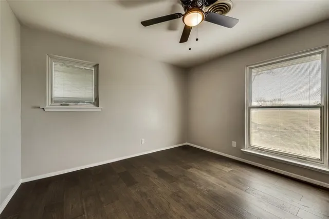an empty room with a window and a ceiling fan
