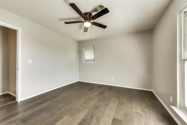 an empty room with wooden floor and ceiling fan
