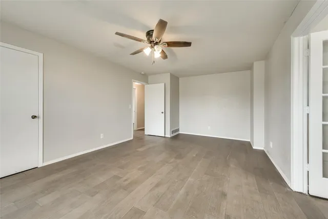 a view of an empty room with chandelier fan and fire place