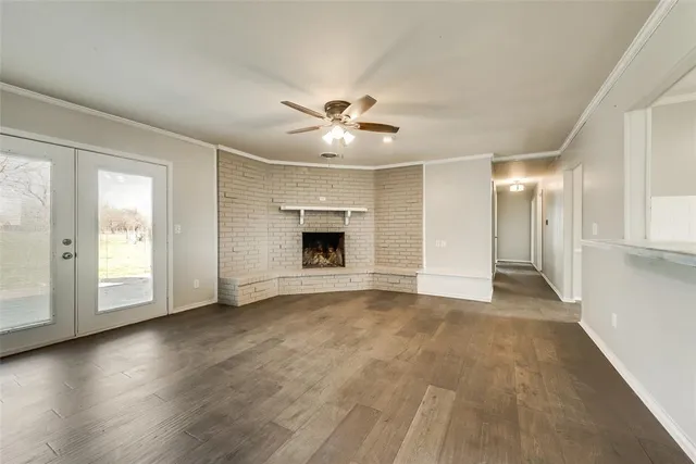 a view of an empty room with chandelier fan and fire place