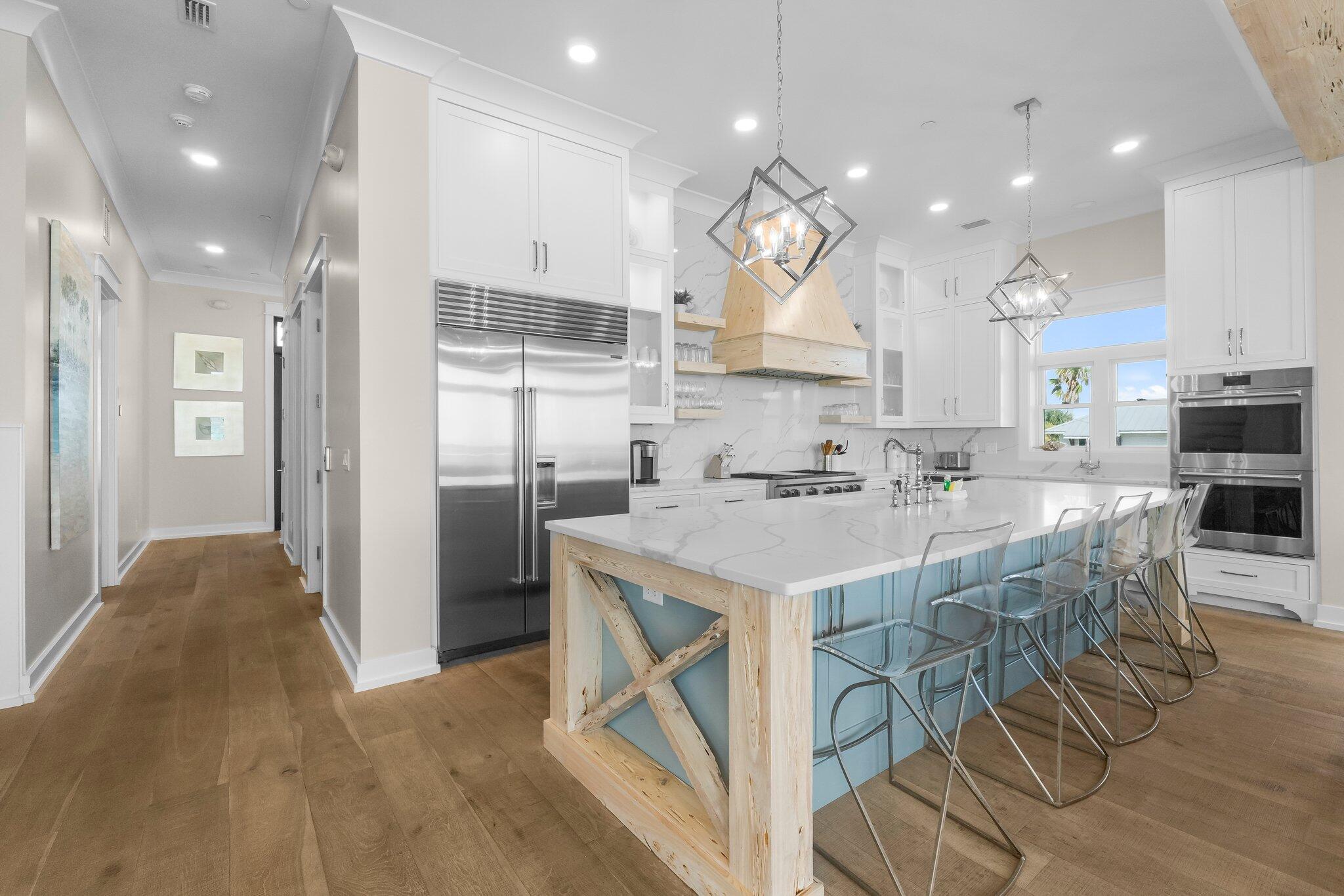 22015 Front Beach Road Panama City Beach, FL 32413 - Photo 23 of 104 a kitchen with kitchen island granite countertop a sink a stove a refrigerator and a dining table with wooden floor