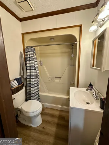 a dining room with wooden floor a chandelier a wooden table and chairs