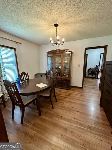 a kitchen with stainless steel appliances kitchen island granite countertop a stove top oven a sink dishwasher a dining table and chairs with wooden floor
