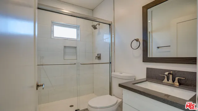 a bathroom with a granite countertop sink toilet a mirror and shower