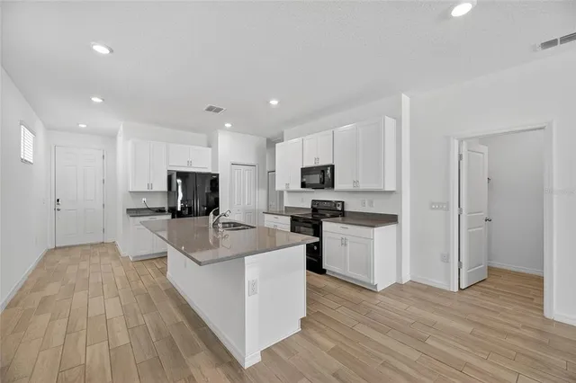 a kitchen with granite countertop a sink stainless steel appliances and white cabinets
