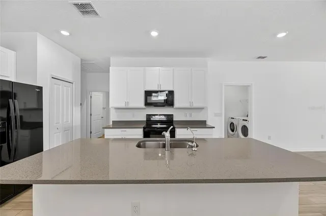 a kitchen with granite countertop a sink a stove top oven a counter space and cabinets