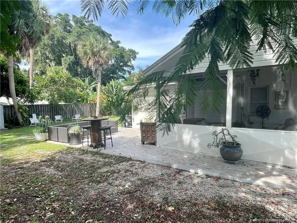 a backyard of a house with table and chairs plants and large trees