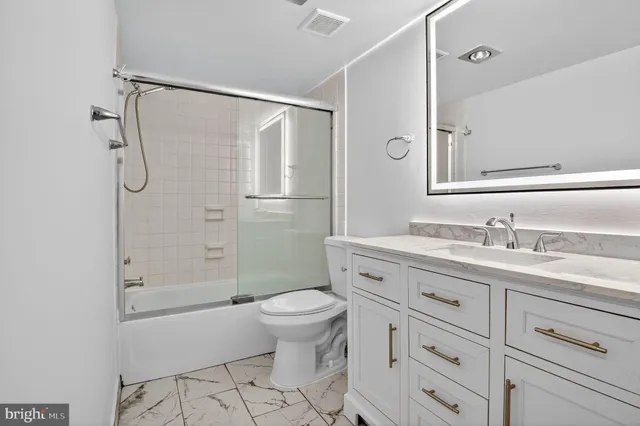 a bathroom with a granite countertop sink toilet and shower