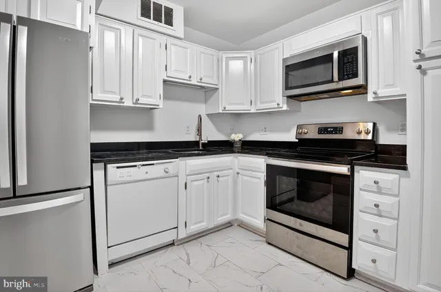 a kitchen with white cabinets stainless steel appliances and sink