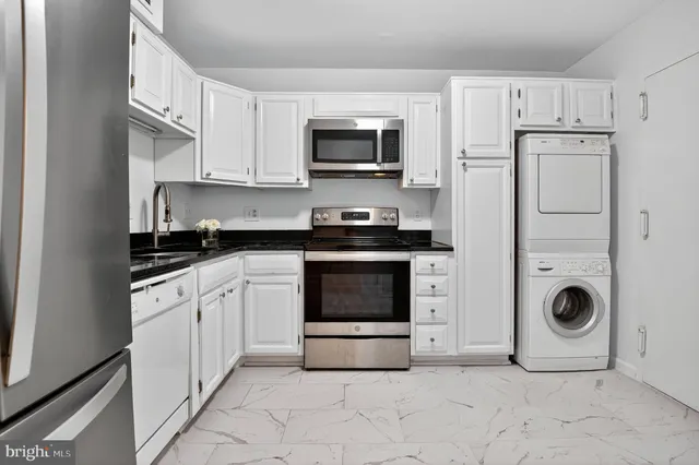 a kitchen with granite countertop a stove top oven and cabinets