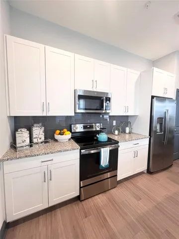 a kitchen with granite countertop white cabinets and stainless steel appliances
