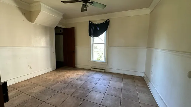 a view of an empty room and window with a ceiling fan