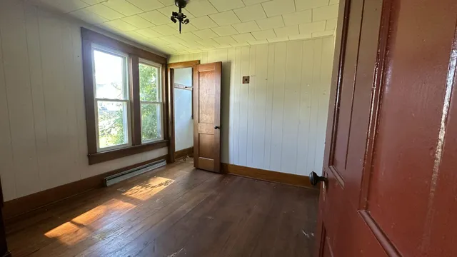 an empty room with wooden floor fan and windows
