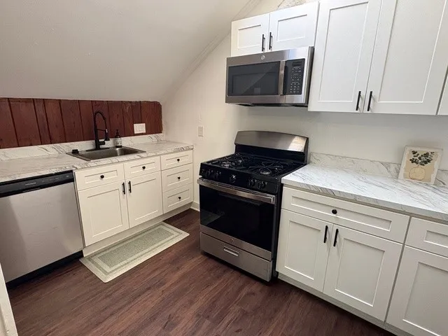 a kitchen with granite countertop cabinets stainless steel appliances and wooden floor