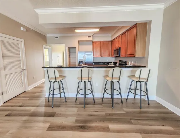 a view of a kitchen with kitchen island granite countertop wooden floor and a refrigerator