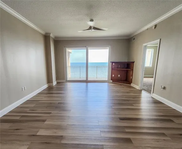 a view of empty room with wooden floor and fan