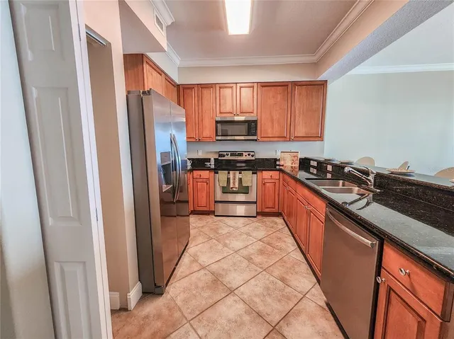 a kitchen with stainless steel appliances granite countertop a stove a refrigerator a sink a stove top oven and a dishwasher next to a window