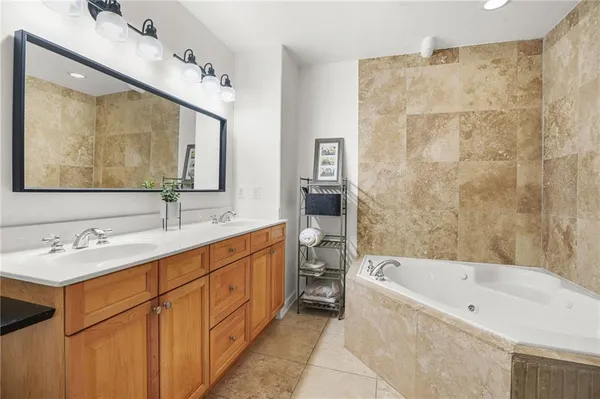 a bathroom with a tub sink double vanity granite and a mirror