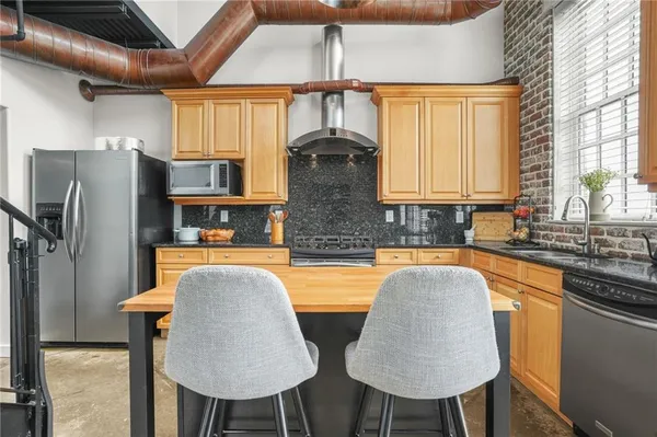 a kitchen with stainless steel appliances granite countertop a kitchen island a stove a table and chairs in it