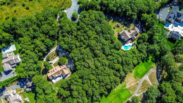 an aerial view of a house with a lush green forest